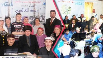 مجموعة متنوعة من الأشخاص في حدث مجتمعي، يجلسون معًا في قاعة مزينة بملصقات إسلامية. يظهر كبار السن والأطفال والشباب، بينما يشارك الجميع في الأنشطة الاجتماعية. الأجواء تعكس الروح الجماعية والتعاون بين الأجيال المختلفة.