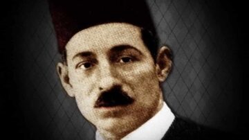 صورة تاريخية لرجل يرتدي الطربوش، ذو لحية وشعر قصير، يظهر تعبيراً جاداً. الخلفية داكنة مع نمط هندسي، مما يبرز ملامح وجهه.