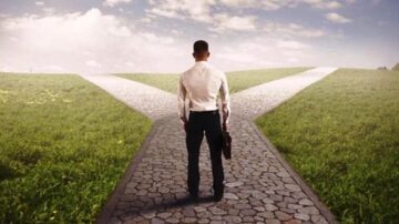 رجل يرتدي بدلة واقف على مفترق طرق في منظر طبيعي، يحمل حقيبة. تشير الاتجاهات إلى خيارين مختلفين تحت سماء زرقاء مع غيوم خفيفة. تعكس الصورة فكرة اتخاذ القرارات والتوجه نحو المستقبل.