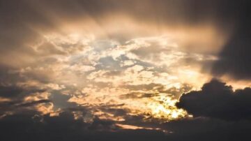 سماء ملبدة بالغيوم مع أشعة الشمس تتسلل من بين السحب، مشهد طبيعي يجسد جمال الغروب والضوء.