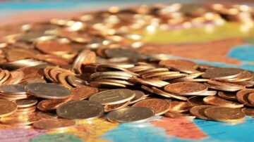 قطع نقدية متنوعة متناثرة على خريطة، تظهر تفاصيل العملات المعدنية مع تباين الألوان والملمس، تعكس مفهوم المال والاقتصاد.