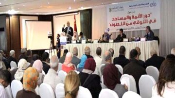 اجتماع لمناقشة دور الأمانة والمساحات في التوقيف من التطرّف، مع متحدث رئيسي على المنصة وجمهور متنوع من الحضور، في قاعة مؤتمرات مزينة بالأعلام.