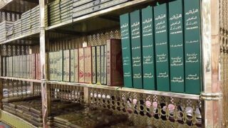 رفوف مكتبة تضم نسخًا متعددة من القرآن الكريم وترجماته المختلفة.