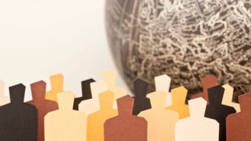 مجموعة من الأشخاص الملونين مصنوعة من الورق، تقف أمام كرة أرضية. تمثل الصورة التنوع والشمولية في المجتمعات.