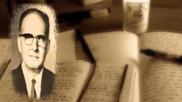 صورة تاريخية لرجل مسن يرتدي نظارات، معلقًا على خلفية دفتر ملاحظات مفتوح وأقلام. تظهر الكتابات على الصفحات بشكل واضح، مما يشير إلى أهمية الكتابة والتوثيق. تعكس الصورة أجواء من الإلهام والإبداع في مجال الأدب.