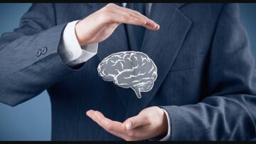 رجل يرتدي بدلة رسمية يمسك بيديه صورة ثلاثية الأبعاد لدماغ، مما يرمز إلى التفكير والإبداع. الخلفية بلون أزرق فاتح تعزز التركيز على الدماغ.