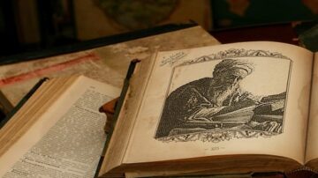 صورة لكتاب قديم مفتوح يظهر رسمًا توضيحيًا لرجل مسن يعمل على كتاب آخر. الخلفية تحتوي على كتب قديمة وأوراق. تبرز التفاصيل الفنية والتاريخية للكتب.