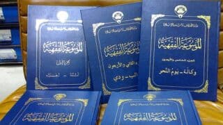 كتب بعنوان "الموسوعة الفقهية" بأغلفة زرقاء ونص ذهبي على كرسي.