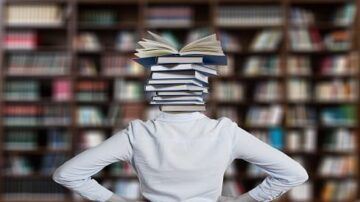 شخص يقف أمام مكتبة تحمل رأسه كومة من الكتب المفتوحة، مما يرمز إلى المعرفة والتعلم. خلفية تحتوي على صفوف من الكتب، تعكس بيئة تعليمية غنية.