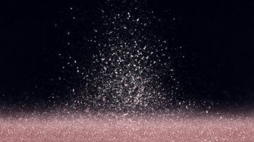 بريق وردي يتناثر في الهواء على خلفية داكنة، مع تأثيرات لامعة تخلق إحساسًا بالعمق والحركة.