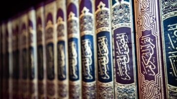 كتب دينية مزخرفة على رف، تظهر تفاصيل غلاف كل كتاب بخط عربي جميل، بألوان غنية وزخارف دقيقة.