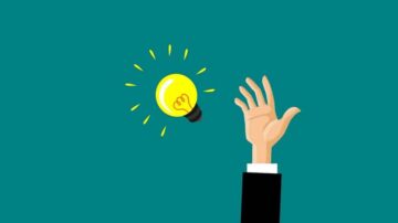 يد مرفوعة تحمل مصباحًا مضيئًا، يرمز إلى فكرة جديدة أو إلهام، مع خلفية زرقاء.