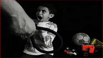 ولد صغير يبدو خائفًا، يصرخ وهو يمسك بحبل في يد شخص بالغ. في الخلفية، توجد ألعاب مثل كرة قدم وشاحنات ملونة، مما يبرز التوتر في الصورة.