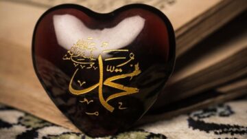 قلب مزين بالخط العربي الذهبي يحمل اسم "محمد" على خلفية من كتاب قديم، يرمز إلى الحب والإيمان.