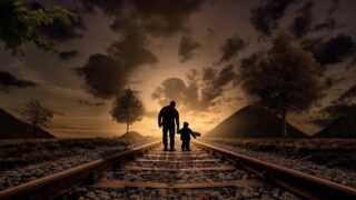 اب يمسك يد طفله اثناء المشي داخل قضبان السكة الحديد