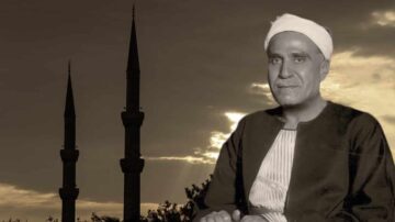 رجل يرتدي زيًا تقليديًا يجلس أمام منظر لغيمات وسماوات داكنة، مع مئذنتين بارزتين في الخلفية، تعكس روح الثقافة الإسلامية والتراث.