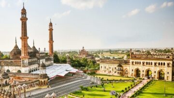 منظر بانورامي لمسجد كبير في مدينةLucknow، الهند. يظهر المسجد مع مآذنه العالية وحدائقه الخضراء المحيطة. تتواجد العديد من المباني التاريخية في الخلفية، مما يعكس التراث الثقافي للمدينة. السماء زرقاء وصافية، مما يضيف جمالاً للمنظر.