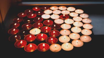 مجموعة من الشموع الملونة، تتكون من شموع حمراء وبيضاء، مضاءة وتضيء بأجواء دافئة، مرتبة بشكل دائري على طاولة.