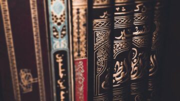 كتب ملونة بتصميمات مزخرفة، مع التركيز على تفاصيل الكتابة العربية والزخارف الجمالية، تظهر في ترتيب منظم على رف.