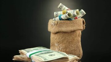 كيس من الخيش يحتوي على نقود ملفوفة، مع وجود كومة من الأوراق النقدية الدولارية بجانبه، تعكس فكرة الثروة والمال.