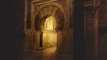 مدخل مزخرف يعود للعصور القديمة، يظهر تفاصيل معمارية رائعة على الجدران والأقواس. الإضاءة الخافتة تبرز جمال النقوش والألوان الدافئة، مما يخلق جوًا تاريخيًا فريدًا.