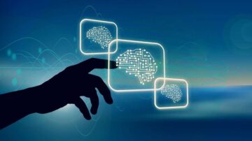 صورة تظهر يد تشير إلى ثلاثة رموز تمثل الذكاء الاصطناعي، مع خلفية زرقاء تعكس التكنولوجيا الحديثة. الرموز تحتوي على أنماط دائرية تشبه خلايا الدماغ، مما يرمز إلى الابتكار والتطور في مجال الذكاء الاصطناعي.