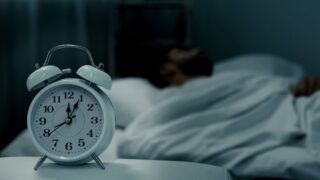 رجل نائم ويضع ساعة منبه لإيقاظه النوم السليم