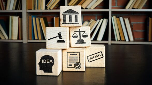 كتل خشبية تحمل رموزًا تمثل فكرة، براءة اختراع، عدالة، ومحكمة، مع خلفية من الكتب.