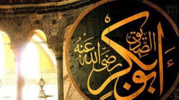 نقش زخرفي يحمل اسم "أبو بكر الصديق" بالخط العربي، يظهر في مكان تاريخي مزين بتفاصيل معمارية إسلامية، يبرز جمال الفن الإسلامي وتأثيره الثقافي.