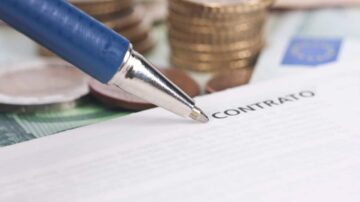 عقد مالي مع قلم أزرق فوقه، مع عملات معدنية في الخلفية.