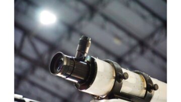 تلسكوب فلكي مع عدسة مكبرة، يظهر تفاصيل التركيب من زاوية قريبة. الخلفية غير واضحة مع إضاءة خافتة.