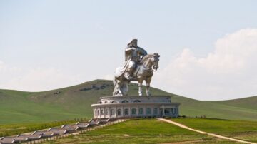 تمثال ضخم لجينغيس خان يمتطي حصانًا، يقع في منطقة مفتوحة مع تلال خضراء في الخلفية. يعكس التصميم المعماري الفريد التفاصيل التاريخية والثقافية. يبرز التمثال كرمز قوي للتراث المنغولي.