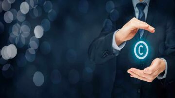 رجل يرتدي بدلة رسمية يمسك برمز حقوق الطبع والنشر مضاءً بين يديه، مع خلفية داكنة وبقع ضوئية، مما يبرز موضوع الملكية الفكرية وحماية الإبداع.