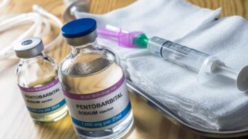 زجاجات تحتوي على حقن بنزوتين وحقنة طبية موضوعة على سطح خشبي، مع مواد طبية إضافية مثل شاش وخرطوم.