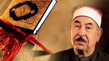 رجل مسن يرتدي عمامة بيضاء، يظهر بجانبه مصحف مفتوح موضوع على حامل. الخلفية تبرز تدرجات دافئة، مما يعكس أجواء روحانية. الصورة تعكس أهمية القرآن في الثقافة الإسلامية.