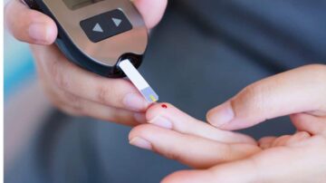 جهاز قياس مستوى السكر في الدم يُستخدم على إصبع شخص لتحديد مستوى الجلوكوز. تظهر قطرة دم صغيرة على الإصبع.