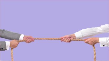 صورة تظهر شخصين يسحبان حبلًا من جهة مختلفة، مع خلفية باللون الأرجواني. تعكس الصورة مفهوم التنافس أو التعاون.