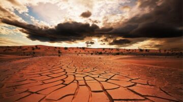 منظر صحراوي يظهر أرضًا متشققة تحت سماء ملبدة بالغيوم. تبرز الكثبان الرملية في الأفق، مما يخلق تباينًا بين الأرض الجافة والسحب الداكنة. تعكس الصورة جمال الطبيعة القاسية في البيئة الصحراوية.