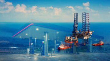محطة وقود حديثة بالقرب من البحر، مع منصة حفر نفطية وأبراجها في الخلفية، وسفينتين تعملان في المياه، تحت سماء زرقاء مع سحب خفيفة.