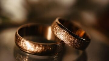 خواتم زفاف ذهبية بتصميم فريد، تعكس الضوء وتظهر تفاصيل دقيقة، مع خلفية ناعمة تضيف لمسة رومانسية.