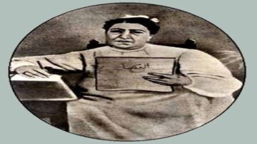 صورة تاريخية لشخص جالس يحمل ورقة مكتوبة، يرتدي ملابس تقليدية. تعكس الصورة فترة زمنية سابقة وتظهر تفاصيل حياة الناس في ذلك الزمن.