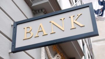 لافتة تحمل كلمة "بنك" مكتوبة بأحرف ذهبية على خلفية رمادية، مع تصميم بسيط.