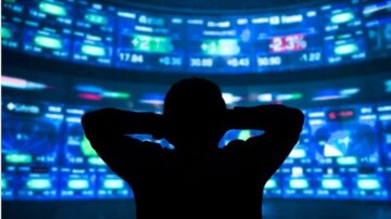 شخص يقف أمام شاشة تعرض بيانات سوق الأسهم مع أرقام متغيرة، مما يعكس حالة السوق المالية والتداول.