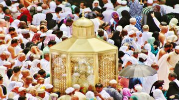 حشود من الحجاج حول الكعبة المشرفة، مع وجود قبة ذهبية تبرز في الوسط. تعكس الصورة روحانية الحج وأجواء العبادة في مكة المكرمة.