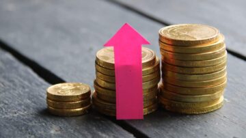 صورة لعملات ذهبية مرتبة في أكوام، مع سهم وردي يشير لأعلى، مما يدل على زيادة أو نمو.