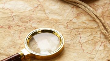 عدسة مكبرة ذهبية على خريطة قديمة مع تفاصيل دقيقة، تعكس روح الاستكشاف والمغامرة.