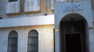 مدخل مبنى تاريخي مع واجهة حجرية، يظهر فوق المدخل كتابة عربية. يحيط بالمدخل نوافذ ذات قضبان حديدية.