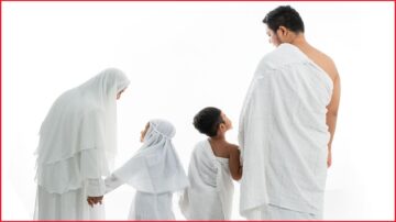 عائلة ترتدي ملابس الإحرام، تتكون من والد ووالدة وطفلين، يستعدون لأداء مناسك الحج. يظهر الوالد متجهاً نحو الكعبة، بينما تحمل الأم يد ابنتها الصغيرة. الطفل الآخر يقف مشدوداً نحو والده. الخلفية بيضاء، مما يبرز الروح الروحية للحظة.