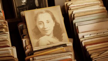 صورة قديمة لامرأة ذات شعر متموج، تظهر بوضوح بين مجموعة من البطاقات القديمة. الإضاءة خافتة تعزز من طابع الحنين في الصورة.