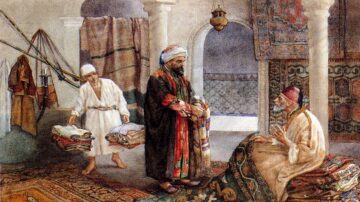 رجل يرتدي ملابس تقليدية يجلس على سجادة في غرفة مزينة بأقمشة ملونة، يتحدث مع رجل آخر يحمل أكوامًا من الملابس. في الخلفية، تظهر تفاصيل معمارية تقليدية وأقمشة معلقة، مما يبرز الأجواء الثقافية والتاريخية.